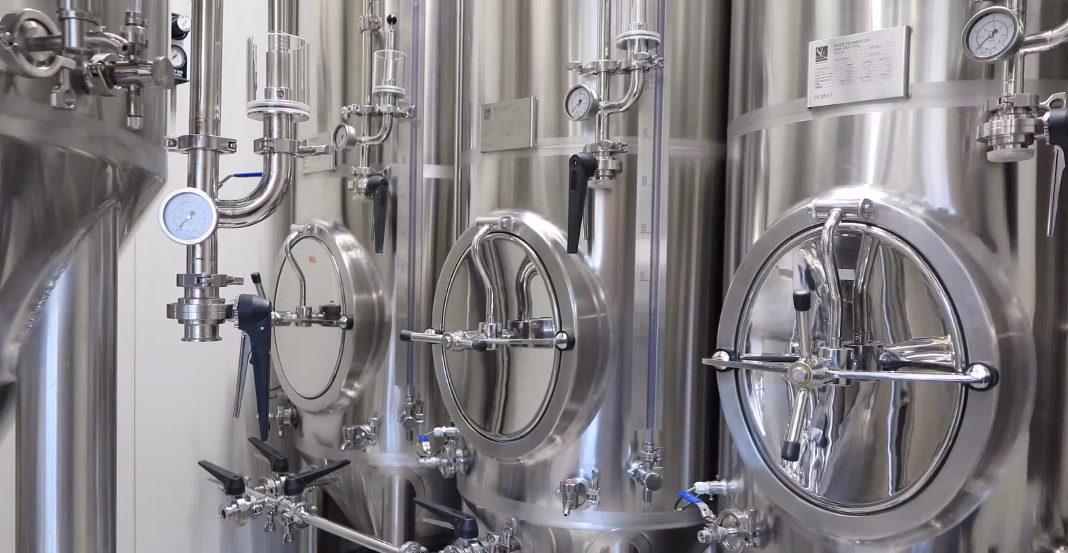 stainless steel products - close up of beer conical fermenter tanks with front manways